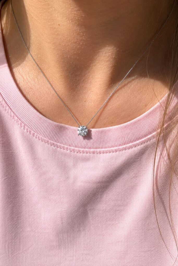Close-up of a minimalist diamond necklace accessory paired with a pastel pink t-shirt, highlighting timeless everyday accessories