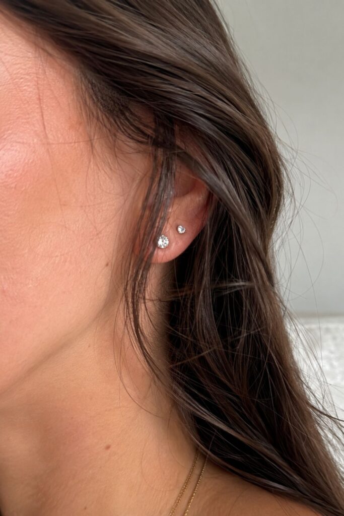 Minimalist silver accessories featuring double diamond stud earrings on a woman with dark brunette hair